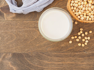  Soy milk in a glass and sackcloth bag on a brown wood background. Top view with copy space. Plant protein.  