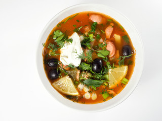 Russian Solyanka soup in a white deep plate. View from above. On a light background