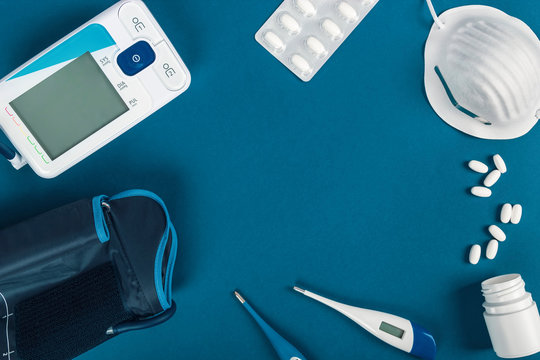 Set of blood pressure monitor, thermometers, mask and pills to care for a sick person.