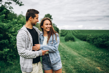 Young loving couple, woman and man, gently hugging with eyes closed on the background of green field. Love Story