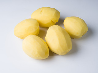 Several peeled potatoes on a white surface. Preparation for cooking. Studio photography