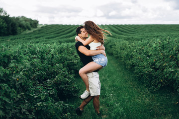 A tender loving couple walking in a field of currant. Man whirls woman in her arms. Love story