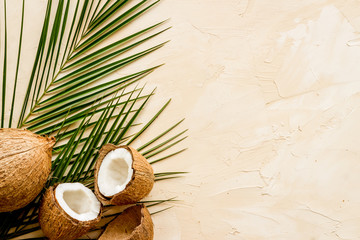 Coconuts and leaves - tropical still life on beige background top-down copy space