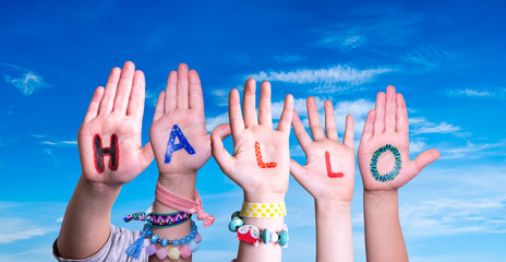 Children Hands Building Colorful German Word Hallo Means Hello. Blue Sky As Background