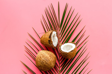Fototapeta na wymiar Coconuts and leaves - tropical still life on pink background top-down
