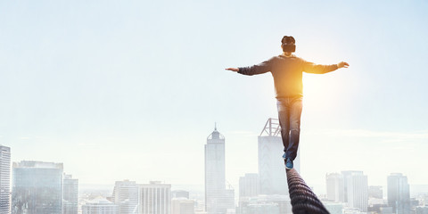 Man wearing virtual reality goggles and balancing on rope