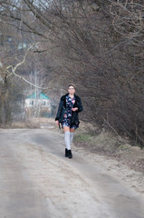 Obraz premium Happy pensive young woman walks along a path in a park on a cloudy spring day