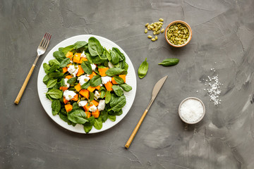 Healthy food concept. Salad with pumpkin and basil on grey background top-down