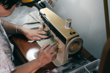 Asian elderly tailor make a cloth by vintage sewing machine.