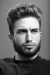 Fototapeta premium Close-up black and white portrait of a young handsome Caucasian male in studio. A man shows different human emotions.