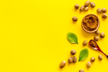 Nutmeg - spices in powder and whole nuts - on yellow background top-down copy space