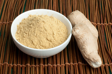 Powdered ginger in a bowl and whole ginger