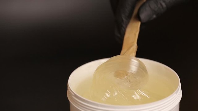 Wax for depilation on a black background. Close-up shugaring paste.