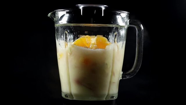 Fruits mixing into blender to making juice at home black background Healthy nutritious food, dieting slow motion