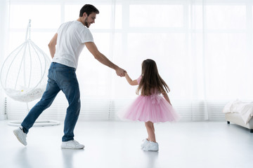 I love you, dad! Handsome young man is dancing at home with his little girl. Happy Father's Day!