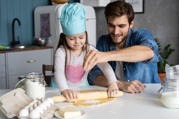 Daddy with daughter baking cake together in home kitchen.