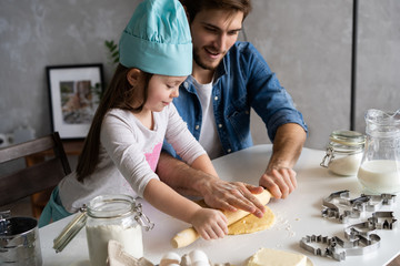 Father and little daughter baking pastries. Family having fun in kitchen and getting ready for a...