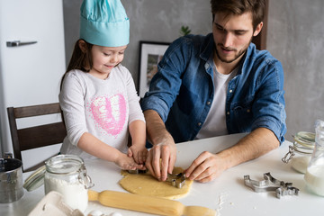 Father and little daughter baking pastries. Family having fun in kitchen and getting ready for a party.