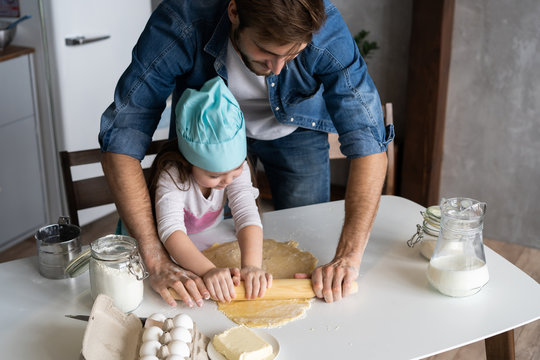 Daddy with daughter baking cake together in home kitchen.