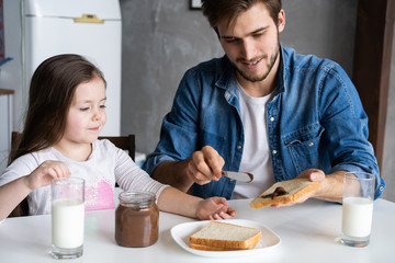 I love you, dad! Handsome young man at home with his little cute girl are having breakfast.