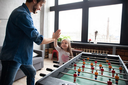 Father And Daughter Playing Table Football At Home