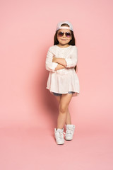 Laughing fashion little girl isolated on pink background.