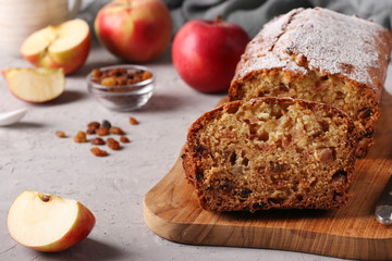 Homemade muffin with apples and raisins on a wooden board on a gray background, close-up