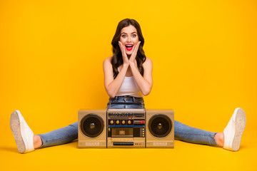 Full length photo of pretty cheerful lady sit floor cozy vintage recorder between spread legs good mood wear white tank-top jeans shoes isolated bright yellow color background