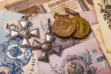 Fototapeta na wymiar Gold and silver coins of the Russian Empire19 - 20 century in the background kopyur.Five rubles Nicholas II.Concept Russian antiques.Saint George cross of Imperial Russia.Antikvariat.
