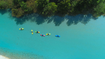 Fototapeta na wymiar TOP DOWN: Flying above a group of tourists kayaking down mesmerizing Soca river.