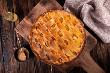 Homemade sweet pie cake with peach on white board on wooden rustic background. Copy space. Top view