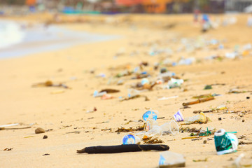 Selective focus on plastic glass, environmental pollution on sandy beach.