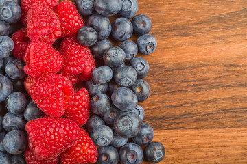 ripe raspberry and blueberry strips on wood background