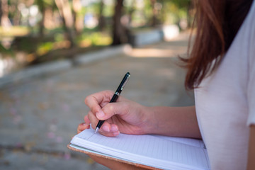 Female sitting writing Record in a small book in the garden comfortably.