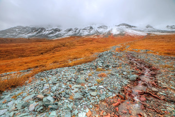 Mountain landscape. Rocks, stones, mountain river, blue sky, clouds. The mountains. covered with snow.