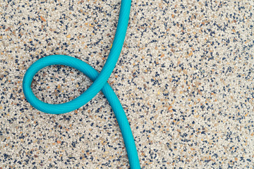 A green blue color rubber tube curl form on the pebble floor