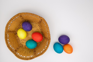 Easter eggs lie in a birch bark plate. Colored eggs lie on a white background.