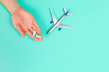  Beautiful young woman's hands holding plane and ear plugs  on pastel  background .
