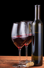 two glasses and bottle with red wine isolated on black