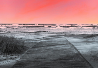 Obraz premium Sunset at a Wooden Walkway at a Baltic Sea Beach with Waves in the Winter