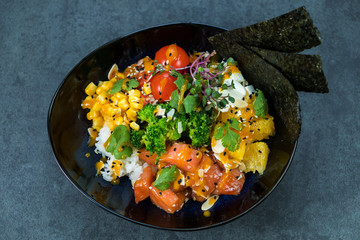 Hawaiian salmon fish poke bowl with, cucumber, tomato, sesame seeds and seaweeds. Diet food