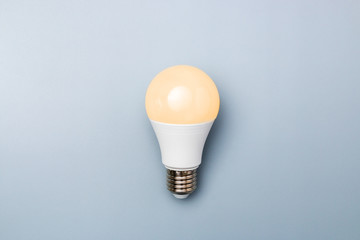 led bulb with orange light against a grey background with copy space. energy efficiency concept