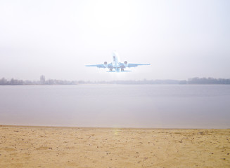 Fototapeta premium Airplane over the lake and sand outside the city. Transport