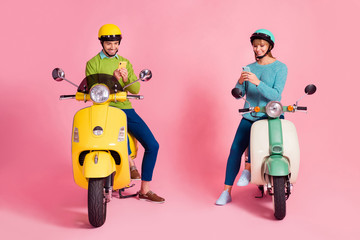 Full body photo of funny lady guy two people driving vintage moped vacation together short stop browsing telephone wear casual sweater headgear isolated pink color background