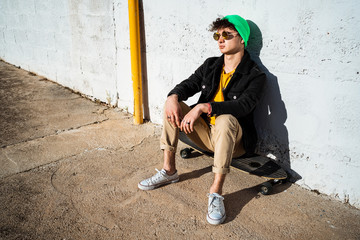 Guy with skateboard on the street dressed modern
