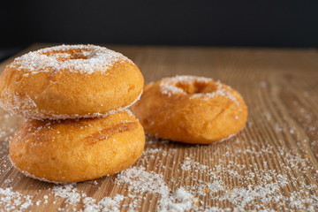 Top view of donuts on wooden board with sugar and black background in horizontal