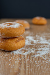Top view of donuts on wooden board with sugar, selective focus and black background in vertical with copy space