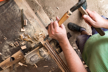 Male carpenter working on old wood in a retro vintage workshop.