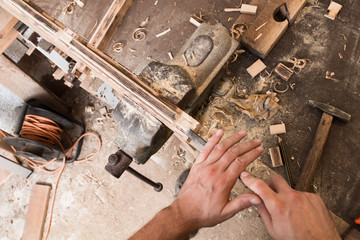 Male carpenter working on old wood in a retro vintage workshop.