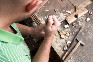 Male carpenter working on old wood in a retro vintage workshop.